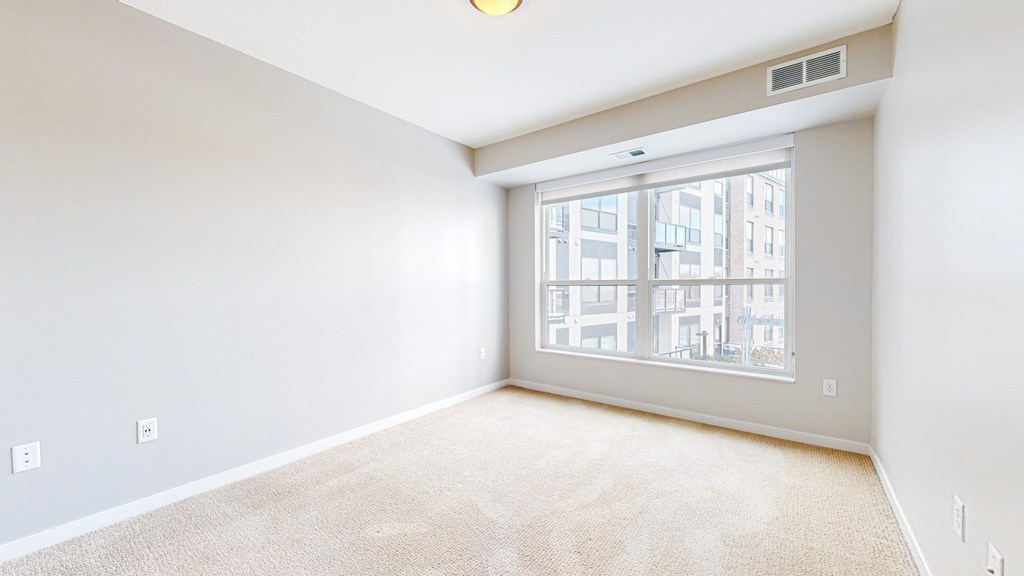 A room with a large window and a carpeted floor.