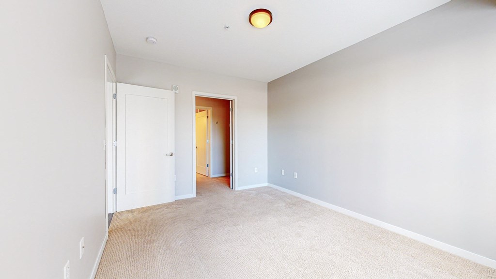 A room with a white door and a carpeted floor.