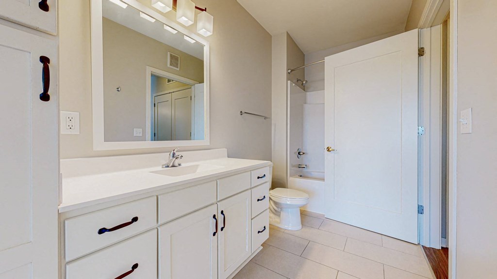 A white bathroom with a sink, toilet, and mirror.
