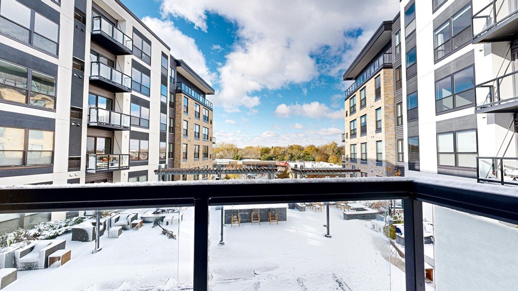 A view from a balcony of a snow-covered courtyard between two buildings.