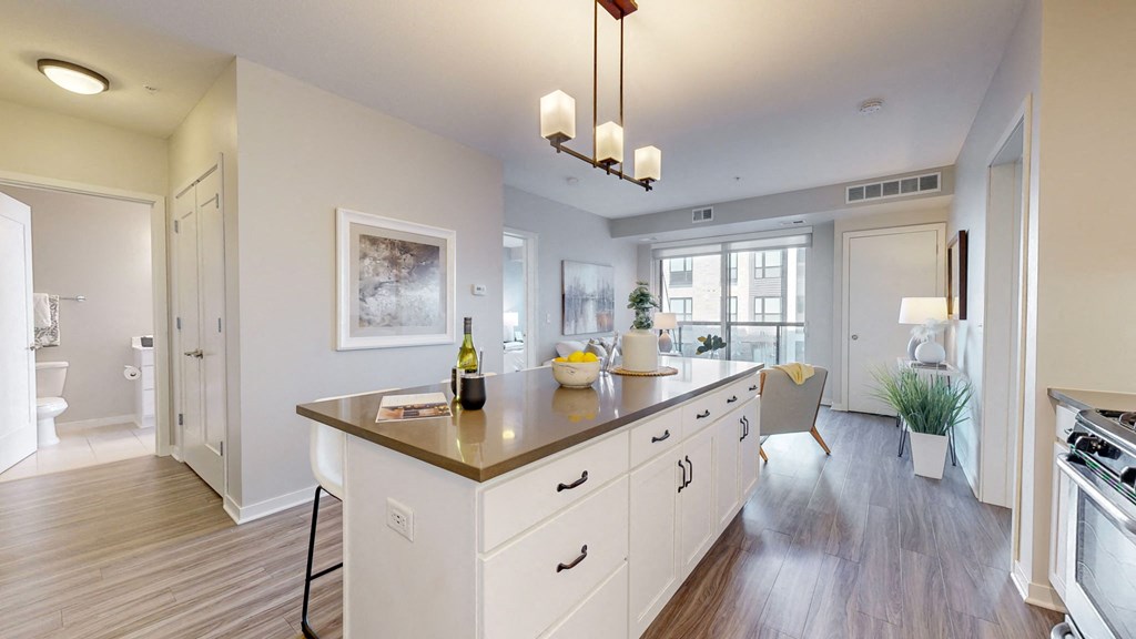 A kitchen with a large island and a dining area in the background.