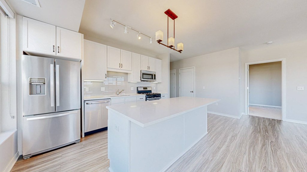 A modern kitchen with a white island and stainless steel appliances.