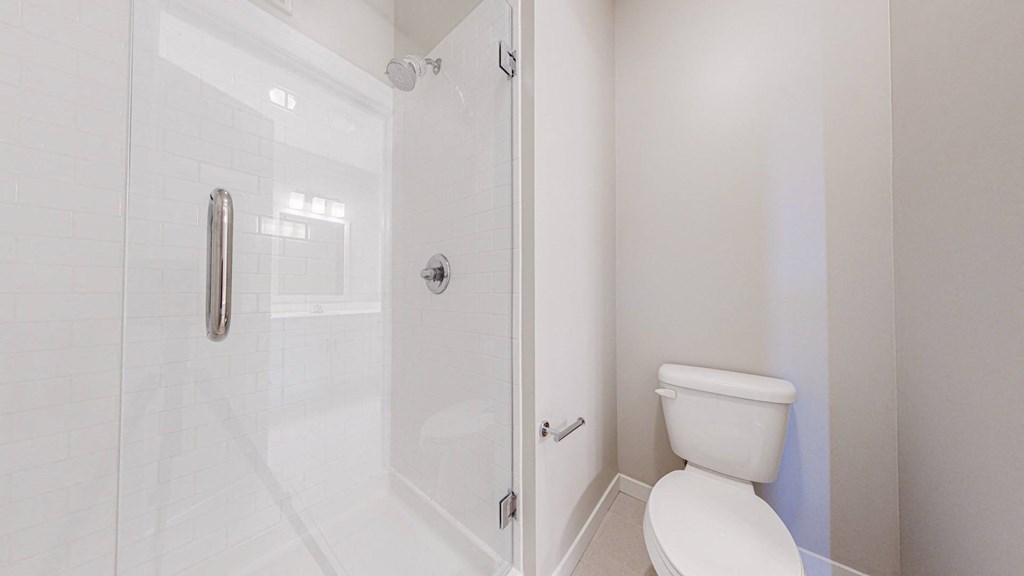 A white toilet in a small bathroom with a glass shower door.
