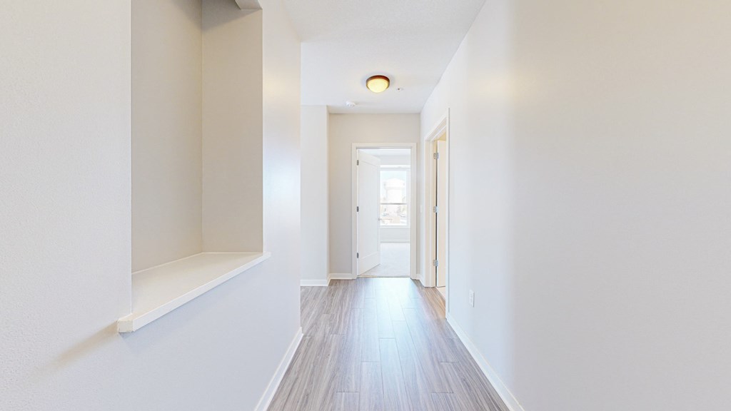A long white hallway with a door at the end.