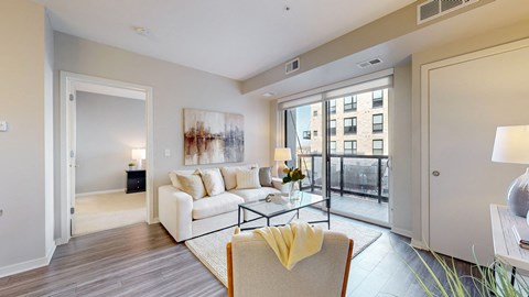A living room with a white couch and a painting on the wall.