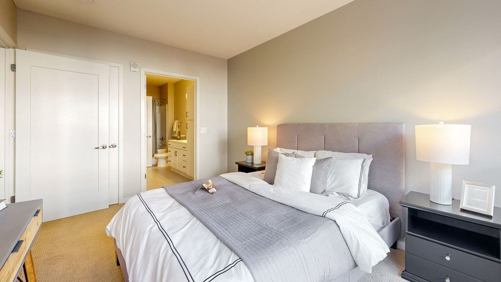 A bedroom with a large bed and a nightstand with a lamp.