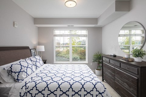 A bedroom with a large bed and a mirror on the wall. A bedroom with a large bed and a mirror on the wall.at The Edison at Avonlea, Lakeville, MN 55044