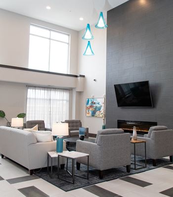 A living room with a grey couch, a fireplace, and a television.at The Edison at Avonlea, Minnesota, 55044