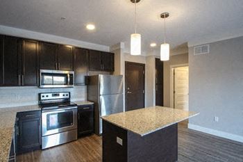 A kitchen with black cabinets and stainless steel appliances.at The Edison at Avonlea, Lakeville, 55044