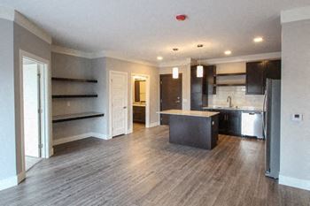 A kitchen with a refrigerator, sink, and cabinets is shown.at The Edison at Avonlea, Lakeville, MN