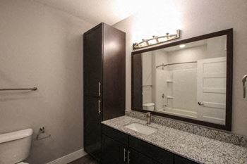 A bathroom with a white tub, sink, and mirror.at The Edison at Avonlea, Lakeville