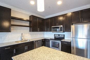 A kitchen with black cabinets and stainless steel appliances.at The Edison at Avonlea, Minnesota