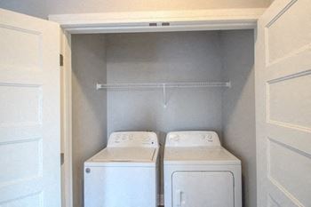 Two white washing machines in a small laundry room.at The Edison at Avonlea, Lakeville