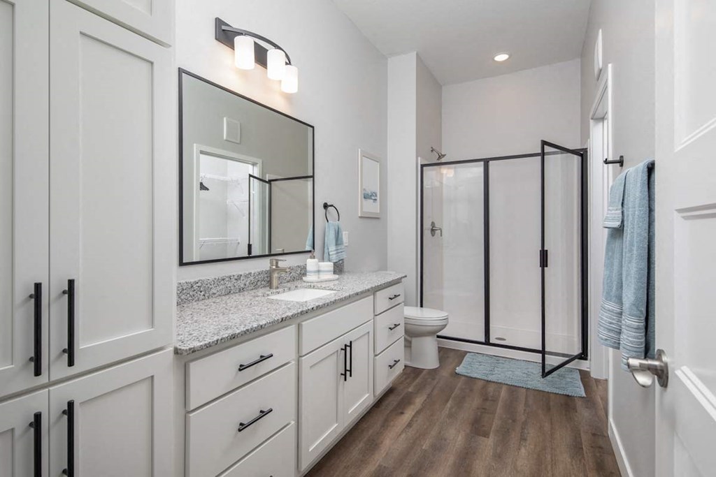 A bathroom with a toilet, sink, and mirror.at The Edison at Maple Grove, Maple Grove Minnesota