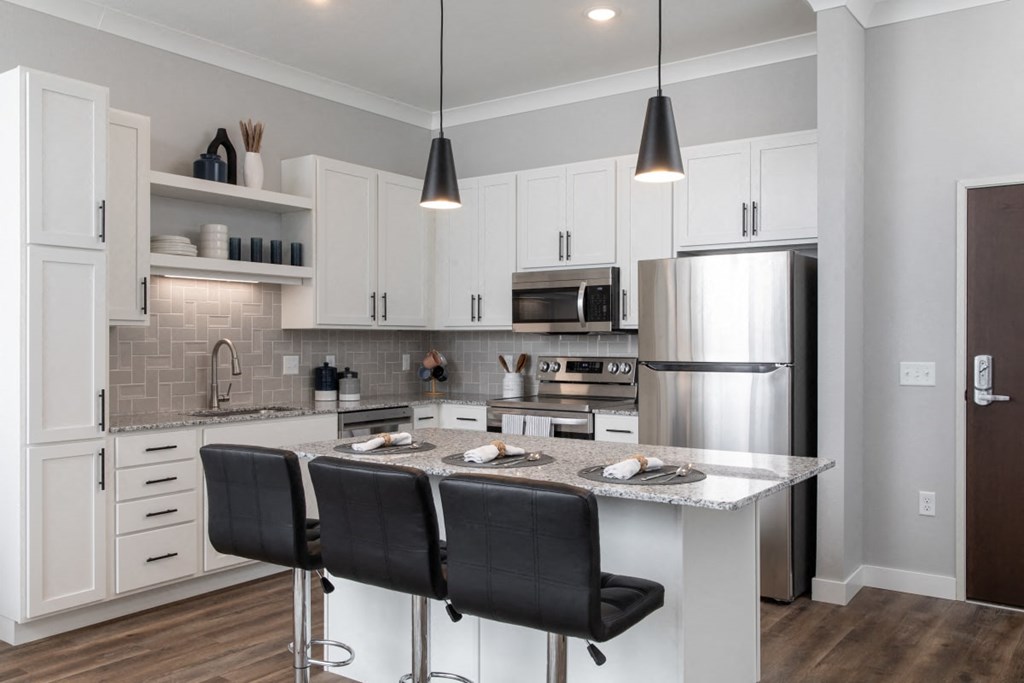 A modern kitchen with a large island and bar stools.at The Edison at Maple Grove, Minnesota, 55311