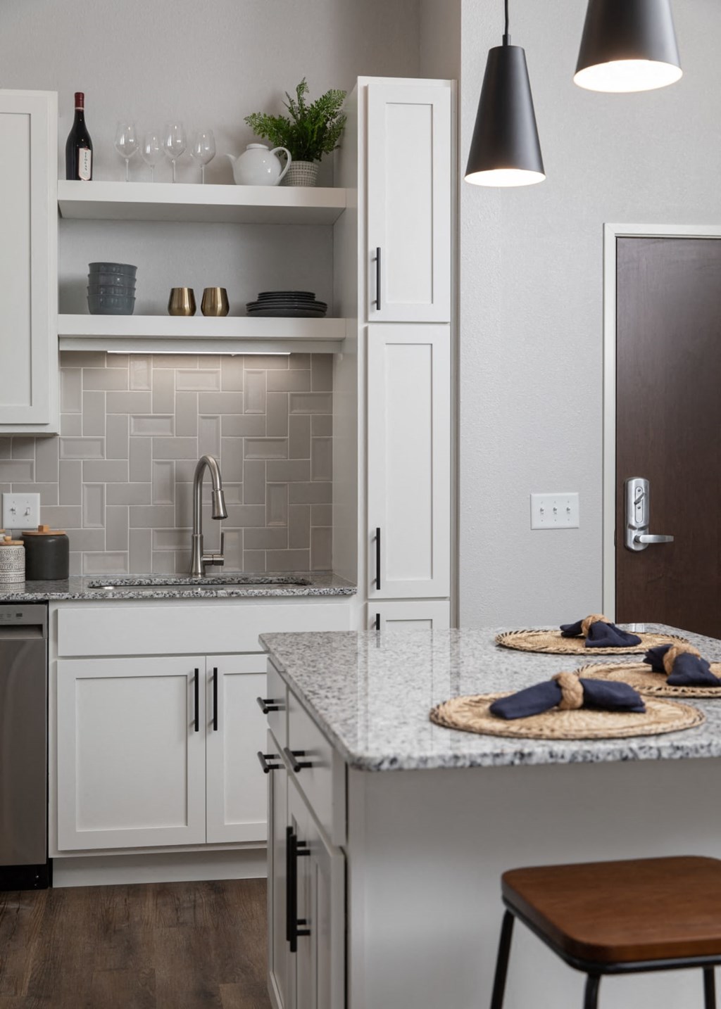 A kitchen with a marble countertop and white cabinets.at The Edison at Maple Grove, Maple Grove, MN