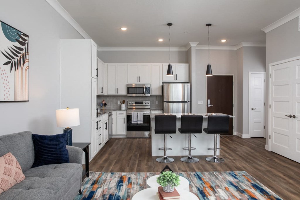 A modern kitchen with a grey sofa and a dining table with four chairs.at The Edison at Maple Grove, Maple Grove