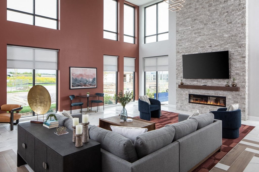 A modern living room with a grey sofa, a fireplace, and a large window.at The Edison at Maple Grove, Minnesota, 55311