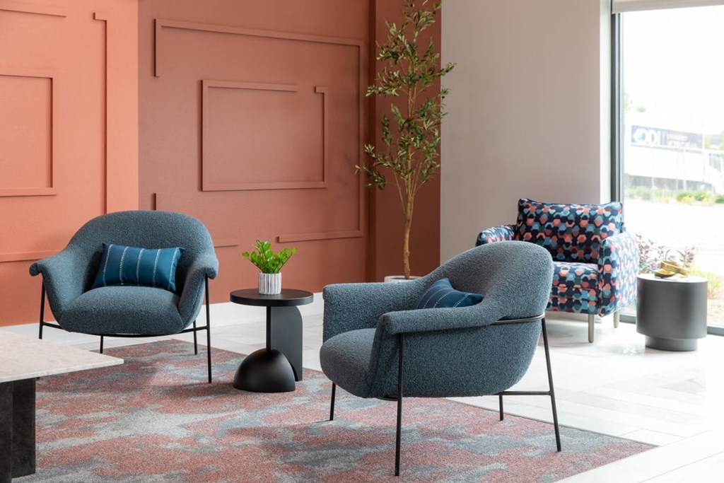A living room with two grey armchairs and a small table with a plant on it.at The Edison at Maple Grove, Minnesota