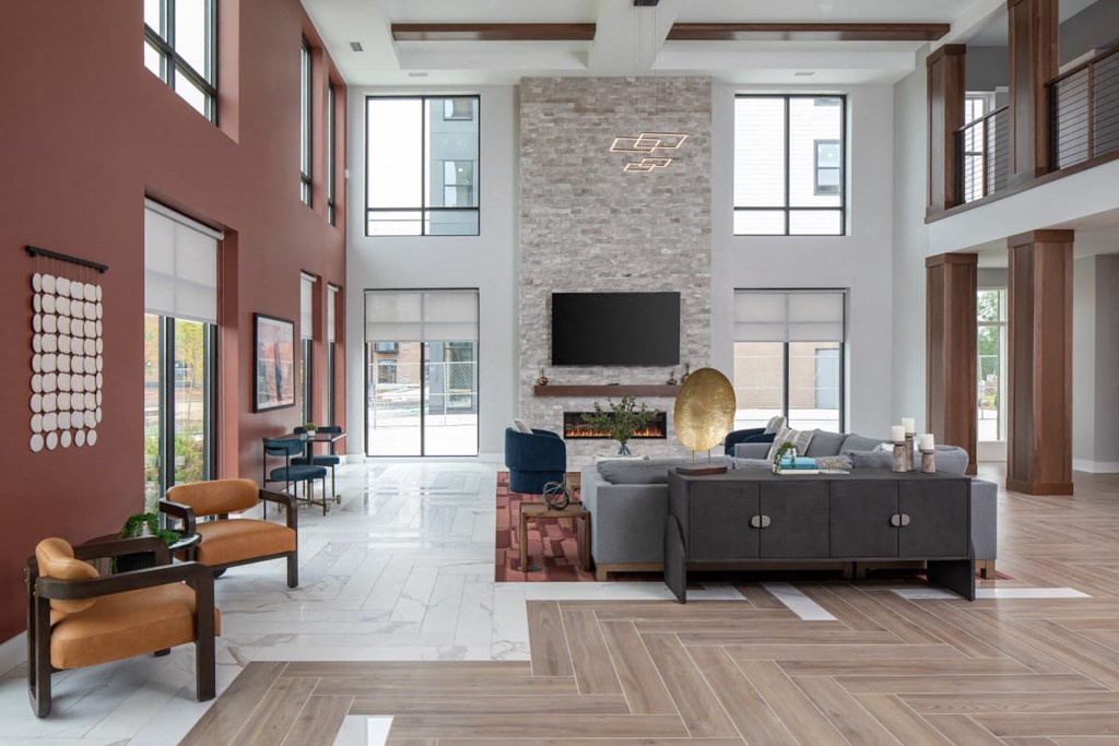 A modern living room with a stone fireplace and a large grey sofa.at The Edison at Maple Grove, Maple Grove, MN