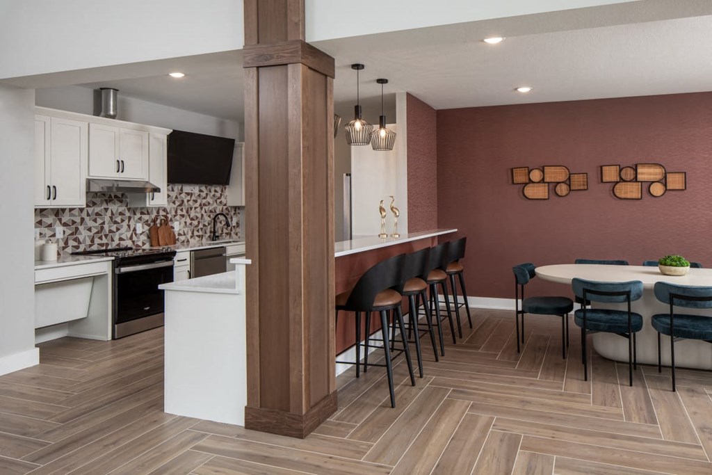 A kitchen with a white island and a dining table with chairs.at The Edison at Maple Grove, Minnesota, 55311