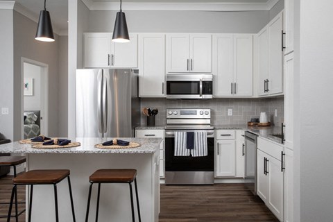 A modern kitchen with white cabinets and a stainless steel refrigerator.