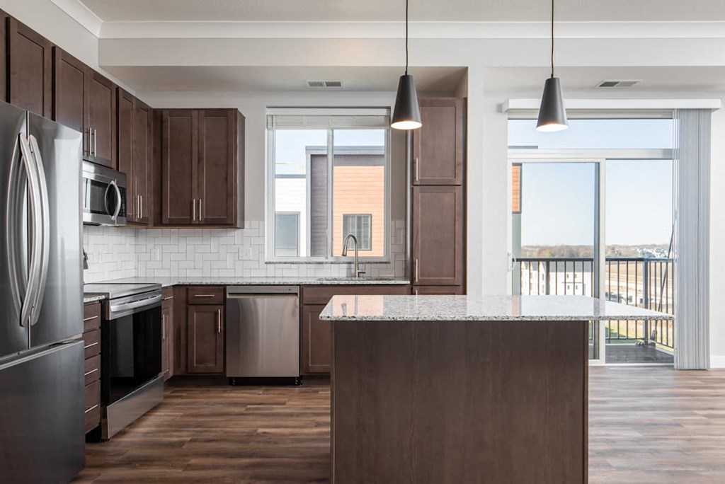 A kitchen with dark brown cabinets and a large island.at The Edison at Maple Grove, Maple Grove Minnesota
