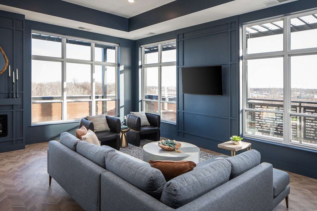A grey couch is in front of a large window in a room with a fireplace.at The Edison at Maple Grove, Maple Grove Minnesota
