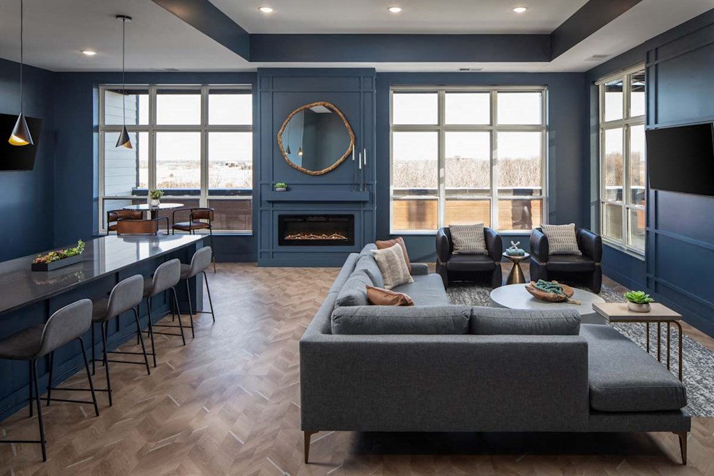 A living room with a grey couch and a fireplace.at The Edison at Maple Grove, Minnesota