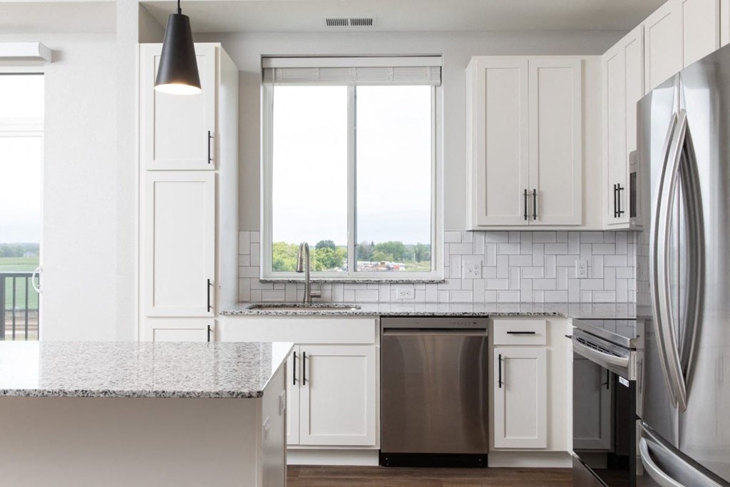 A modern kitchen with white cabinets and stainless steel appliances.at The Edison at Maple Grove, Maple Grove