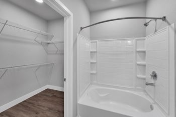 A white bathroom with a walk-in shower and a wooden floor.at The Edison at Maple Grove, Maple Grove Minnesota