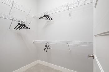 A white closet with clothes hangers.at The Edison at Maple Grove, Maple Grove, 55311