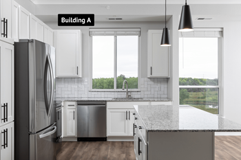A modern kitchen with white cabinets and a black refrigerator.at The Edison at Maple Grove, Maple Grove, 55311