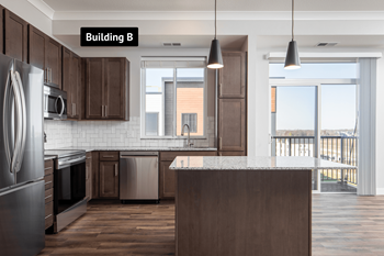 A kitchen with dark wood cabinets and a large island.at The Edison at Maple Grove, Maple Grove, MN