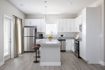 A modern kitchen with a white island and stainless steel appliances.at The Edison at Maple Grove, Maple Grove