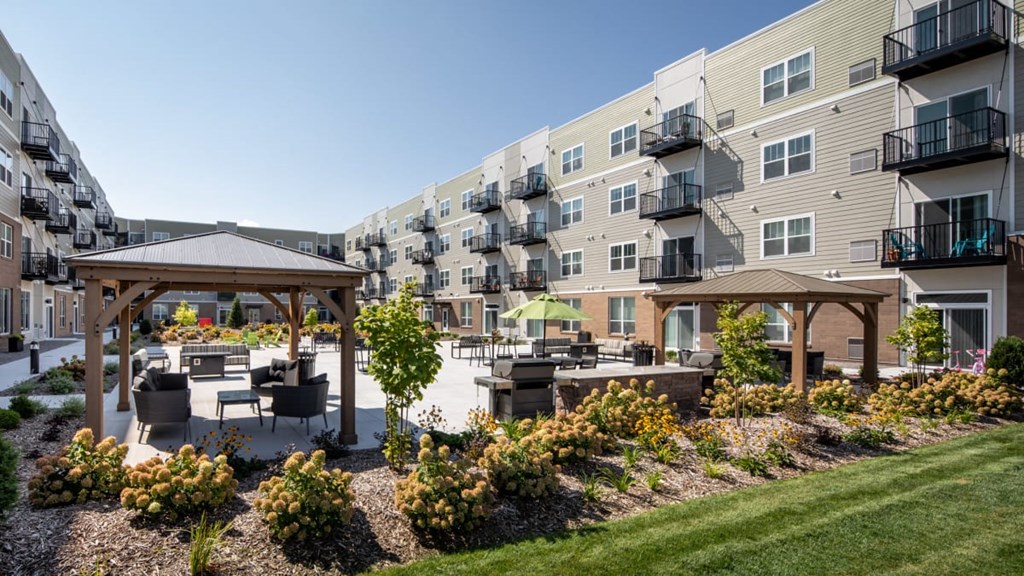 A sunny day at a residential complex with a gazebo and landscaped gardens at The Edison at Rice Creek I and II, Shoreview, MN .