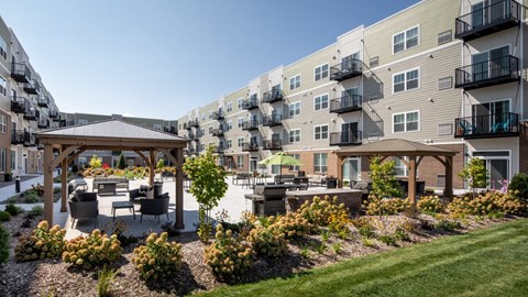 A sunny day at a residential complex with a gazebo and landscaped gardens at The Edison at Rice Creek I and II, Shoreview, MN .