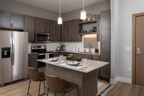 A modern kitchen with a stainless steel refrigerator, microwave, and dining table set for two.