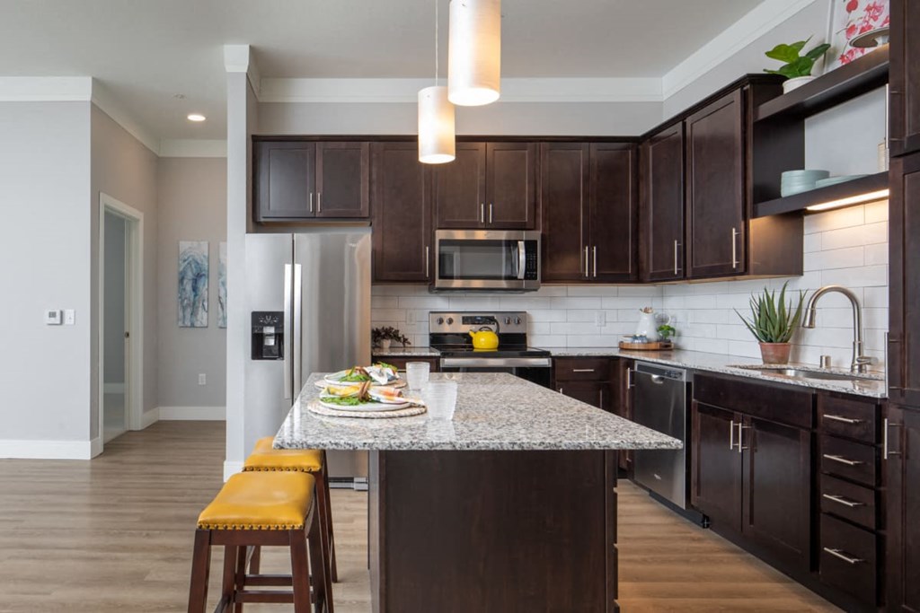 A kitchen with brown cabinets and a granite countertop at The Edison at Rice Creek I and II, Minnesota
