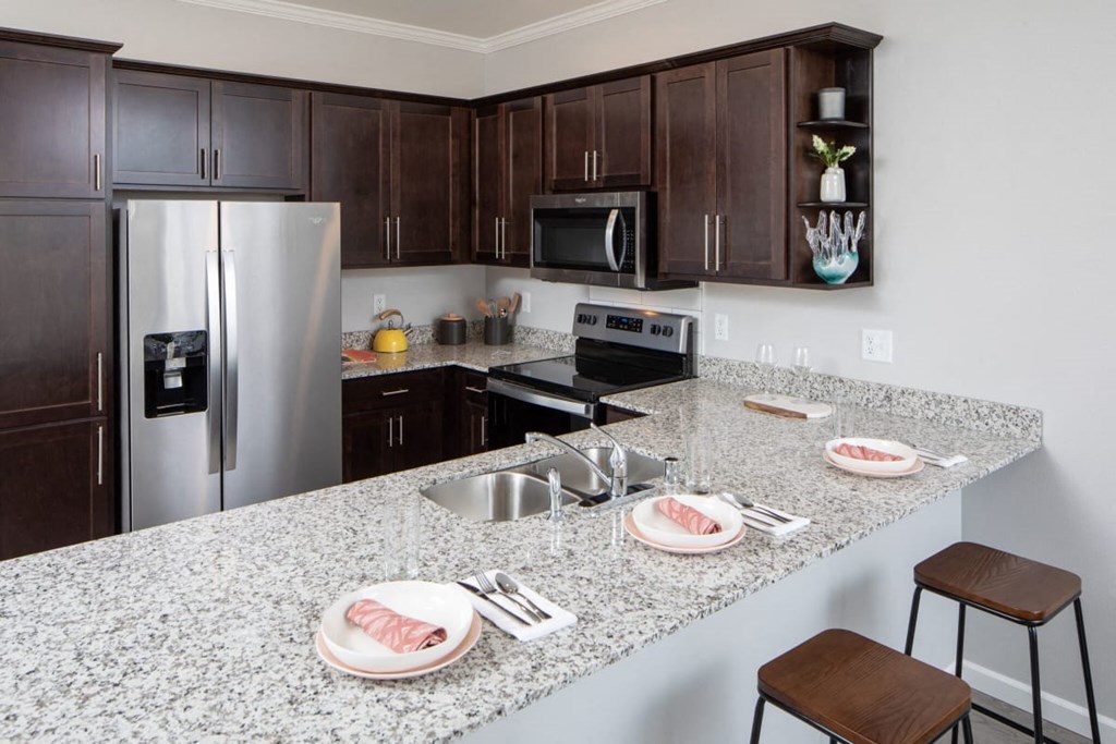 A kitchen with granite countertops and dark wood cabinets.at The Edison at Rice Creek I and II, Minnesota
