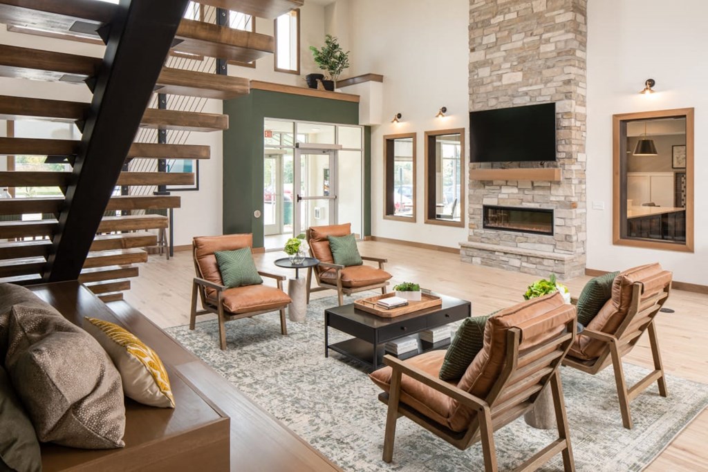 A living room with a stone fireplace and a staircase at The Edison at Rice Creek I and II, Shoreview Minnesota