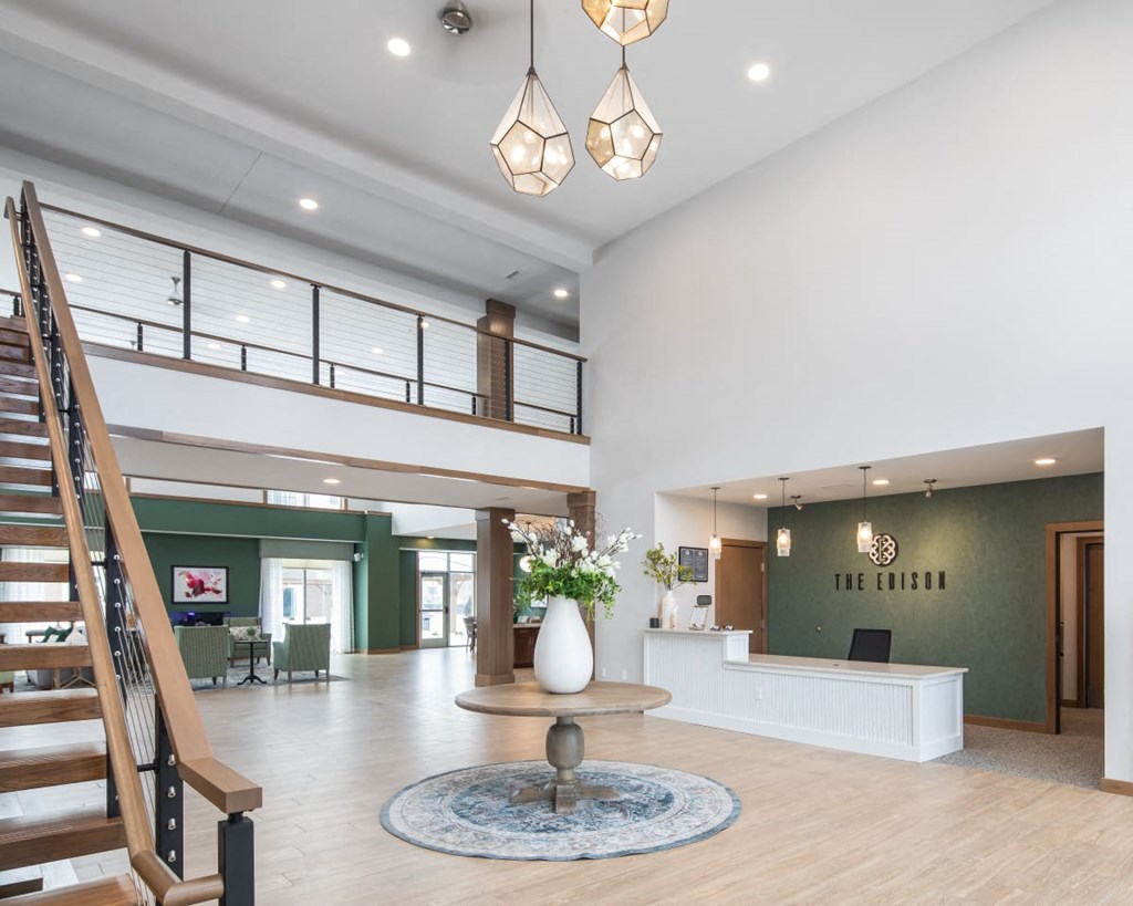 A reception area with a white reception desk and a staircase.at The Edison at Rice Creek I and II, Shoreview Minnesota