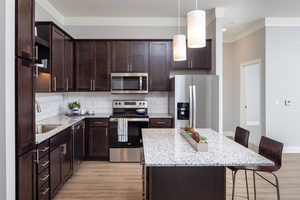 A kitchen with dark wood cabinets and a granite countertop at The Edison at Spirit, Shoreview