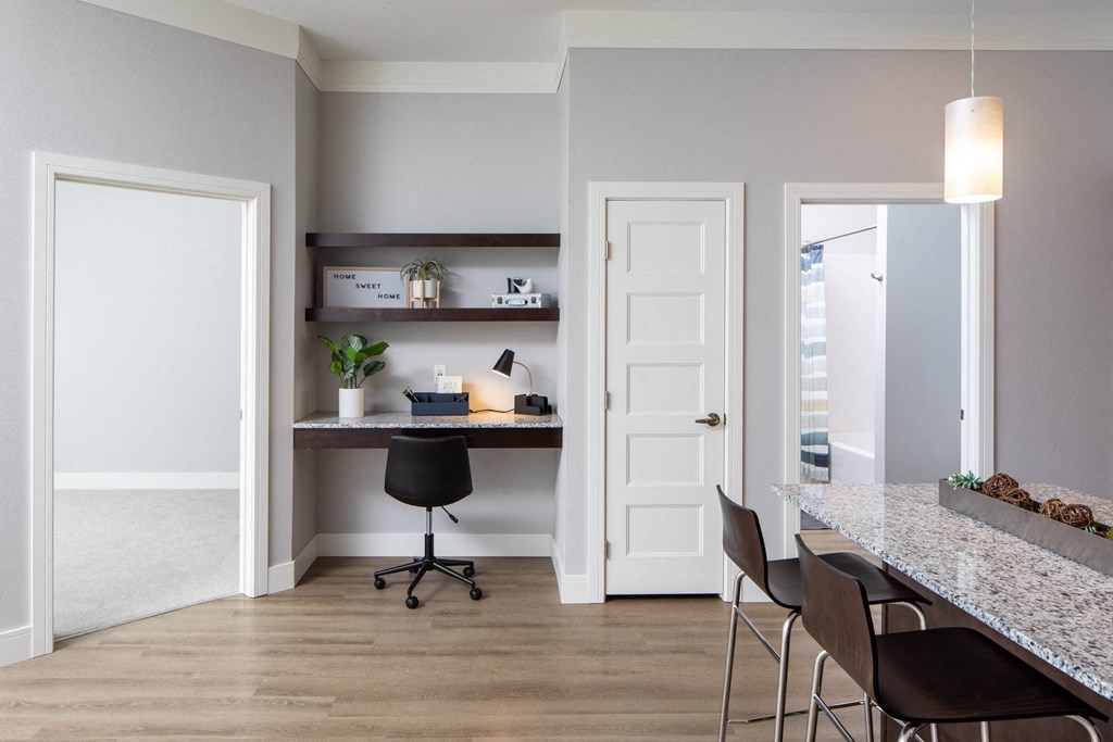 A home office with a desk, chairs, and a shelf with decorative items at The Edison at Spirit, Lakeville Minnesota