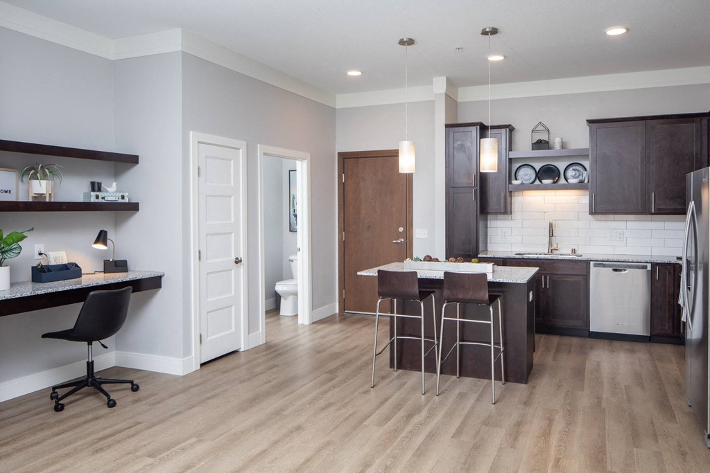 A modern kitchen with dark brown cabinets and a white countertop at The Edison at Spirit, Lakeville Minnesota