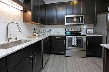 A modern kitchen with black cabinets and stainless steel appliances at The Edison at Spirit, Lakeville, MN