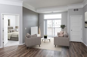 A living room with a grey couch and a wooden floor.at The Edison at Maple Grove, Minnesota