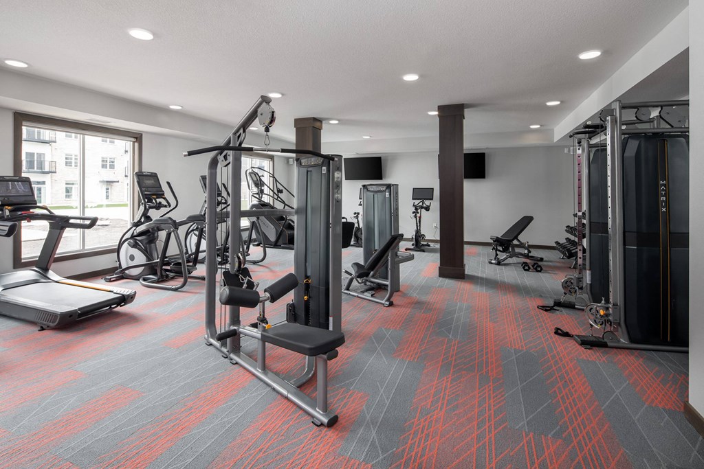 A gym with a variety of equipment including treadmills, weights, and exercise machines at The Edison at Woodbury, Woodbury