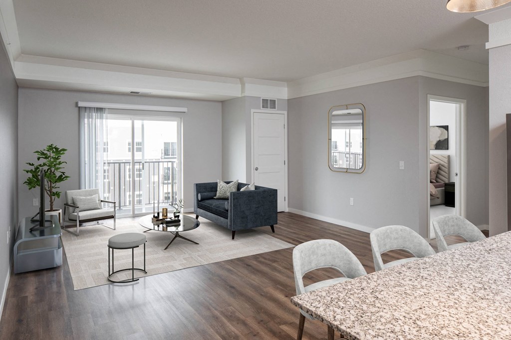 A living room with a grey couch, a white chair, and a round table at The Edison at Woodbury, Woodbury, 55129