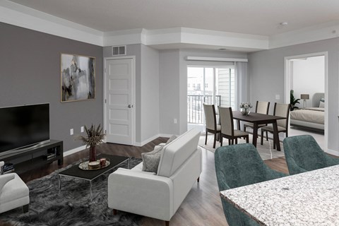 A living room with a grey couch, a black television, and a coffee table with a vase of flowers on it.